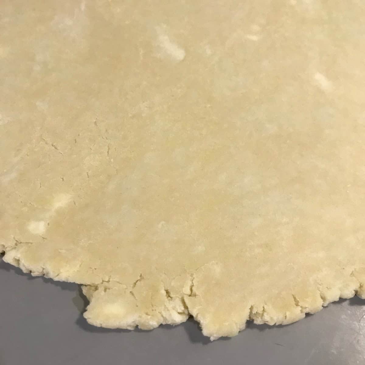 Rolled out pie dough, with visible butter chunks.