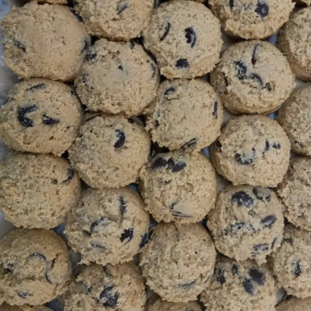 Unbaked chocolate chip cookie dough balls on a sheet tray