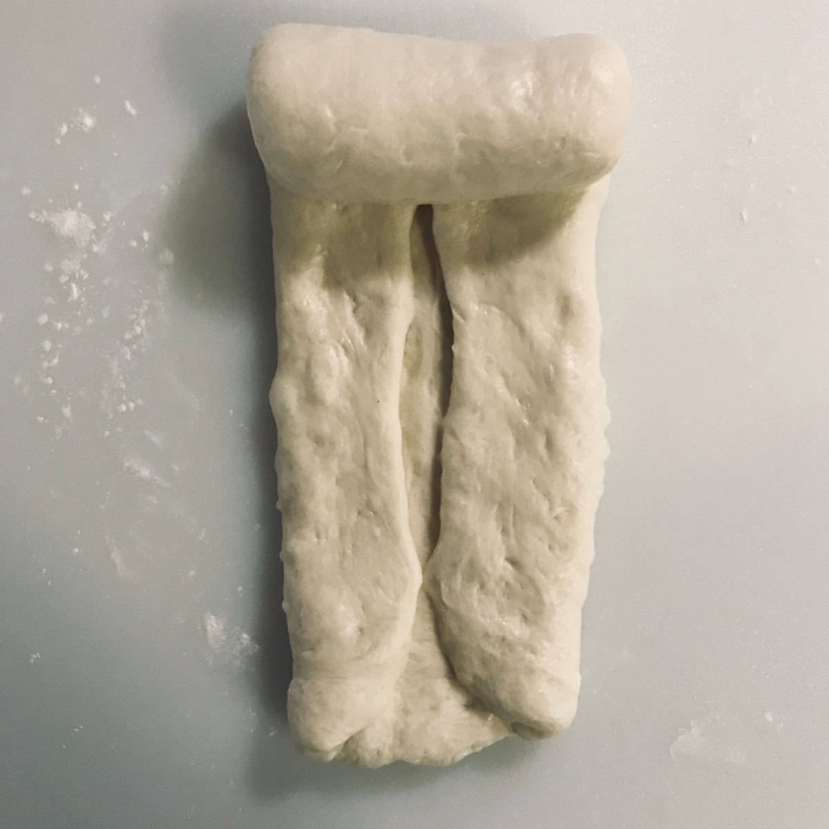 Shokupan milk bread dough being rolled from one end to another