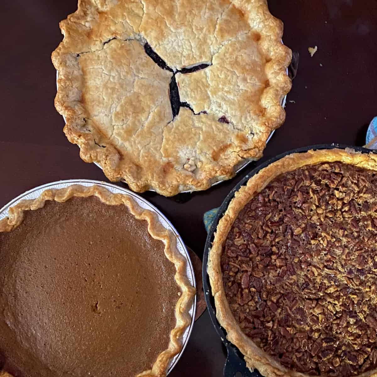 pumpkin, pecan and double-crust blueberry pies on a table.