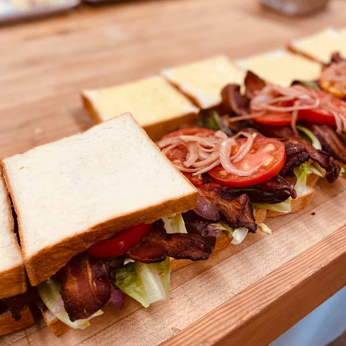 Bacon, lettuce, tomato being assembled on shokupan.
