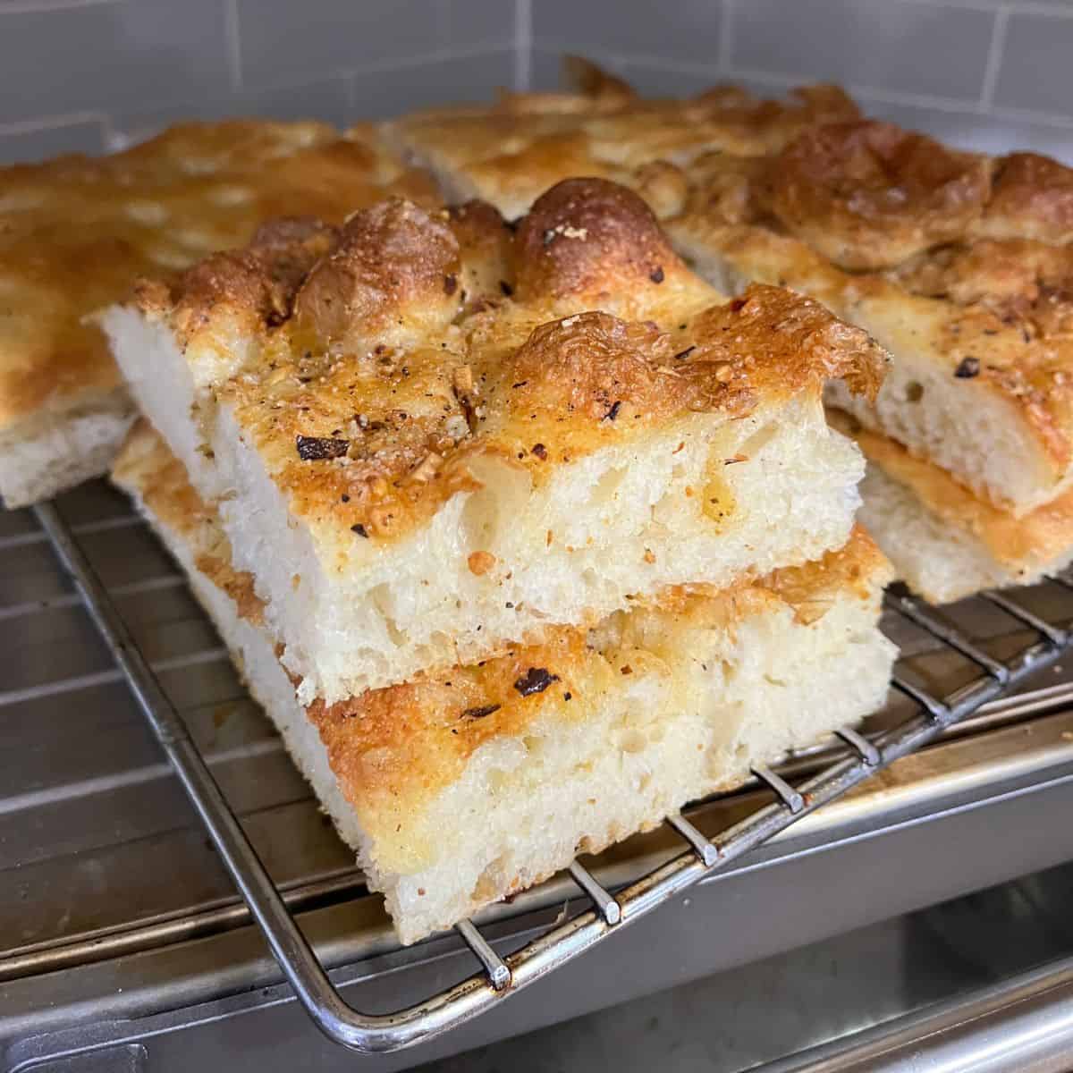 Several pieces of sandwich focaccia sliced and on cooling rack.