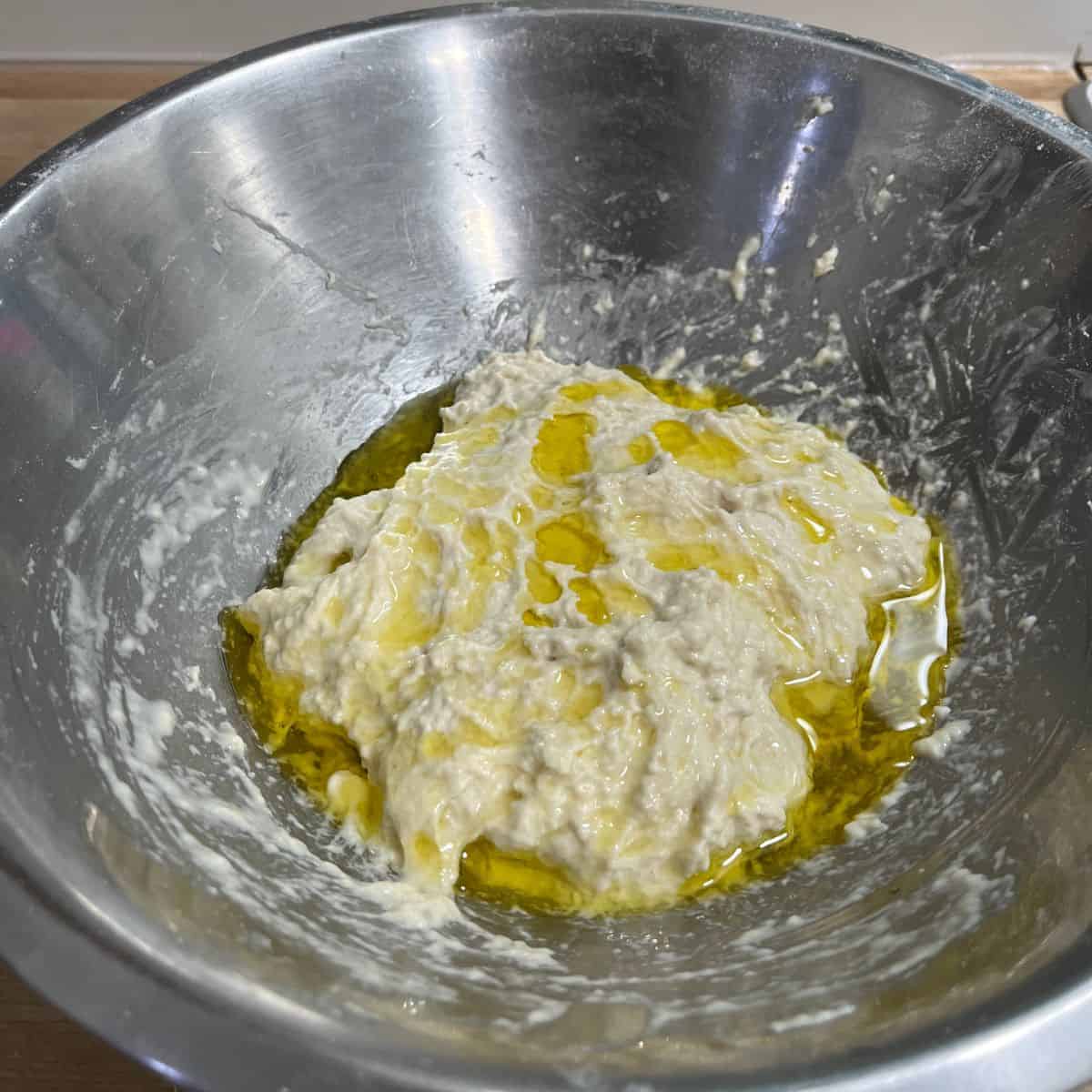 A shaggy mass of focaccia dough with olive oil on top.