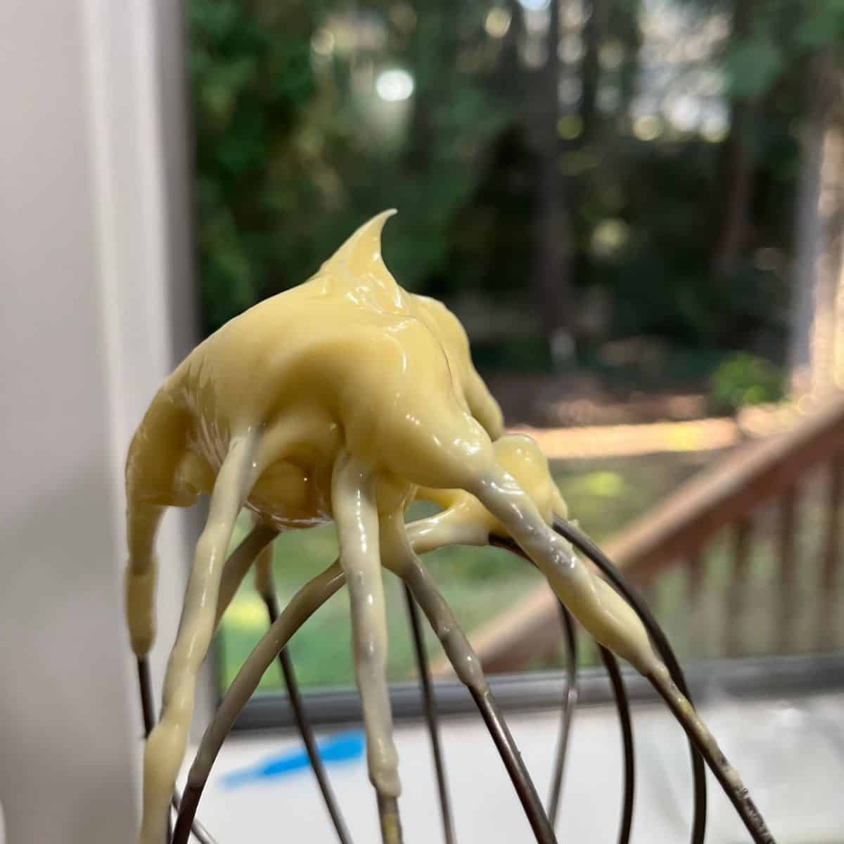 Finished mayonnaise on the tip of the whip, showing medium peaks.