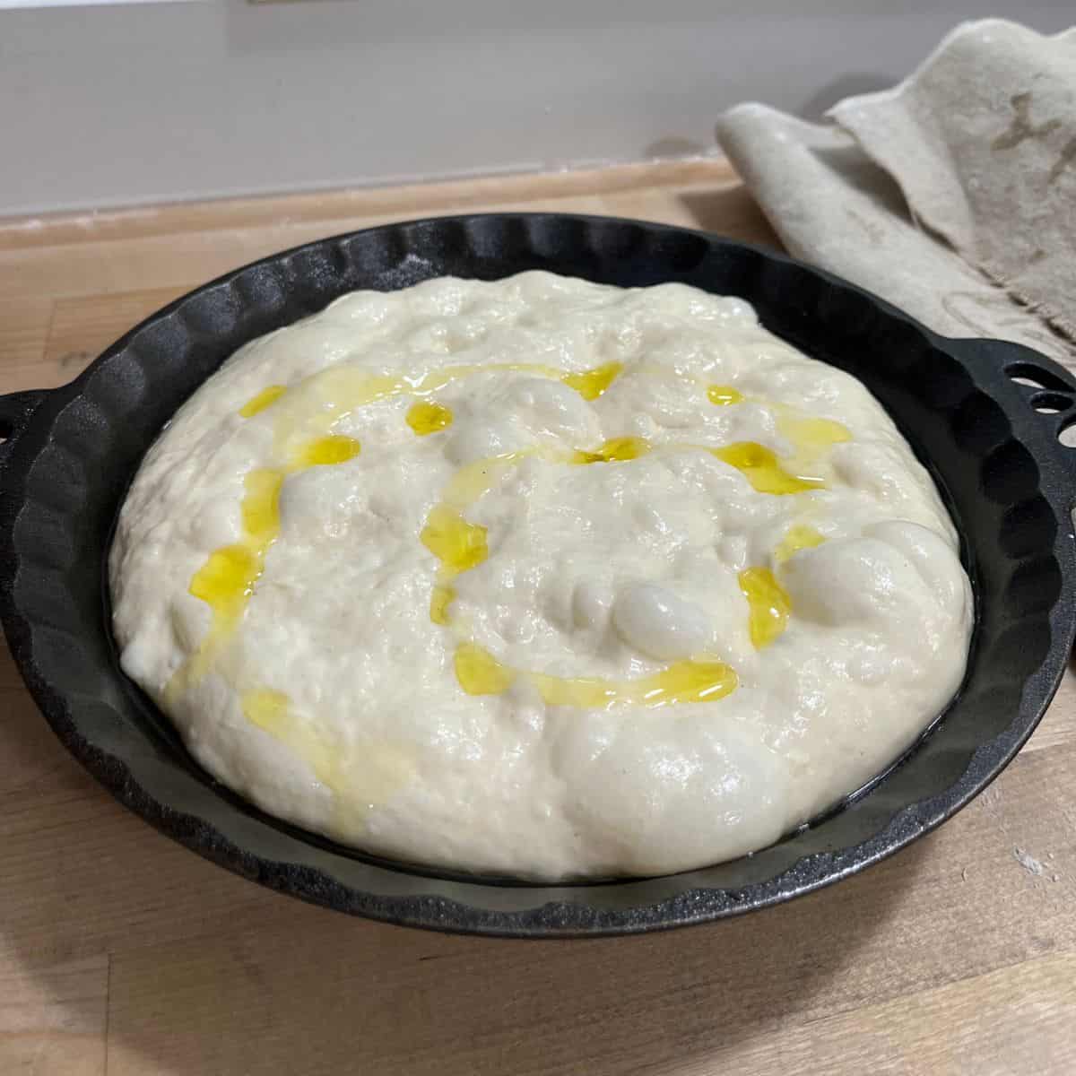 Focaccia dough is puffy and fills the cast iron pan.