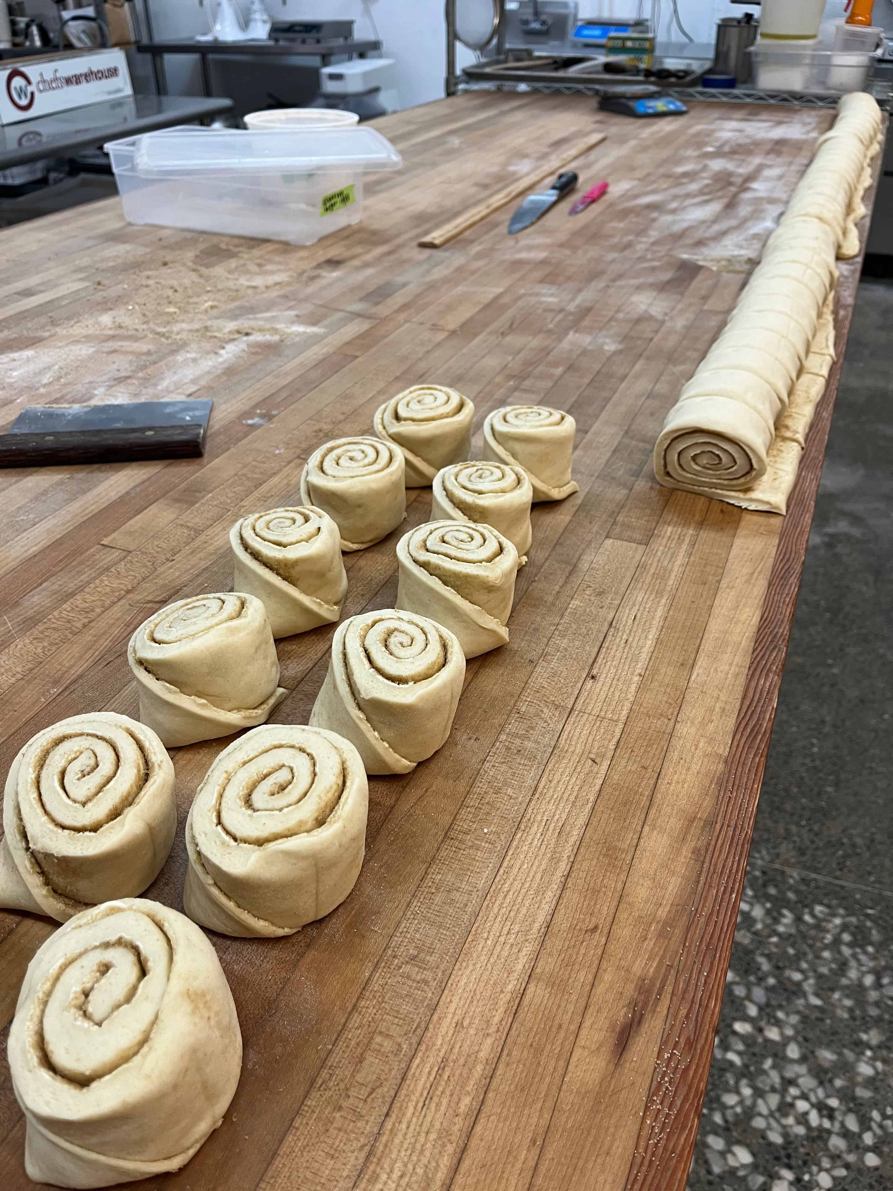 rolled and cut cinnamon trolls on a baker's bench