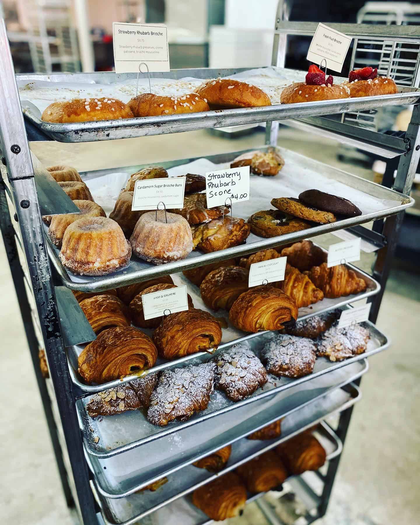 A speed rack with lots of trays of pastries.