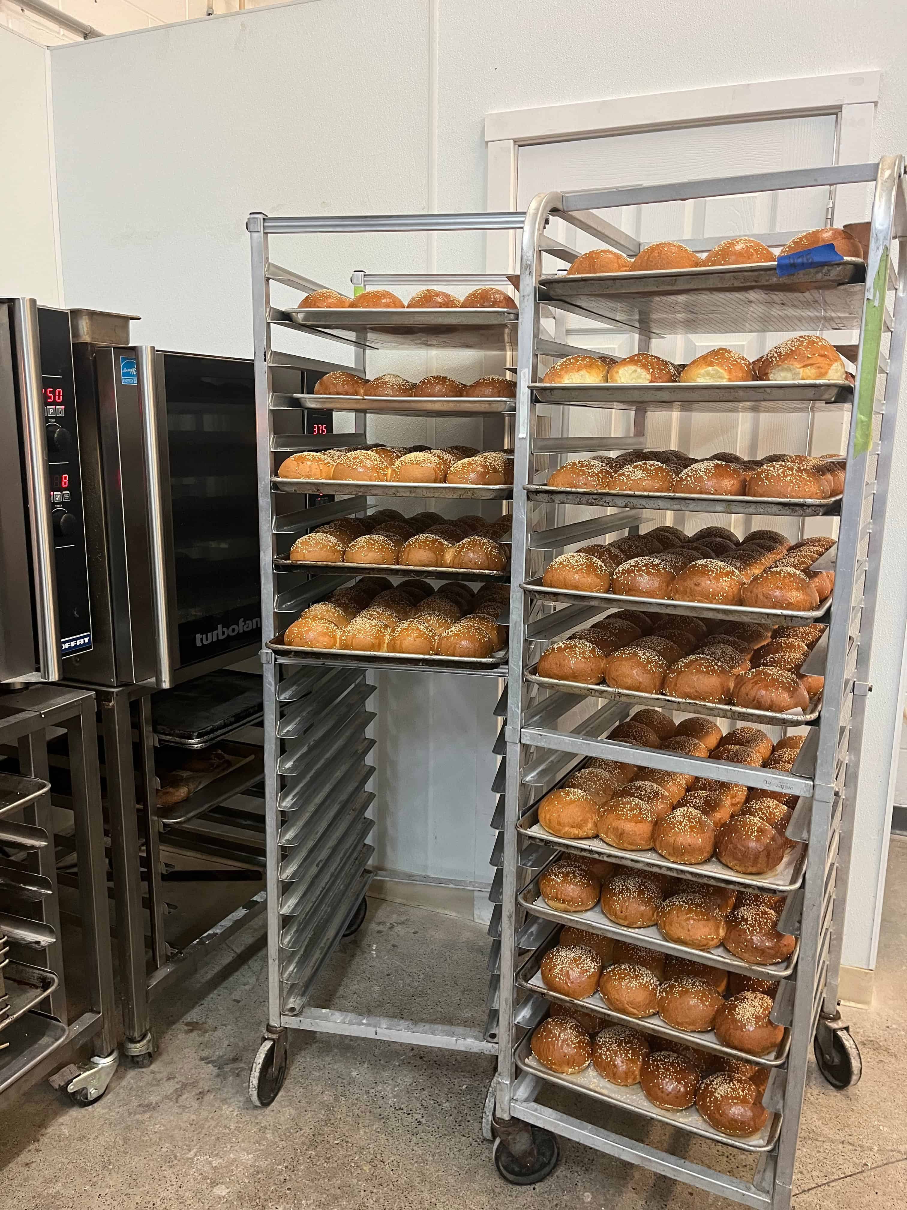 Two speed racks with baked brioche buns on sheet trays.