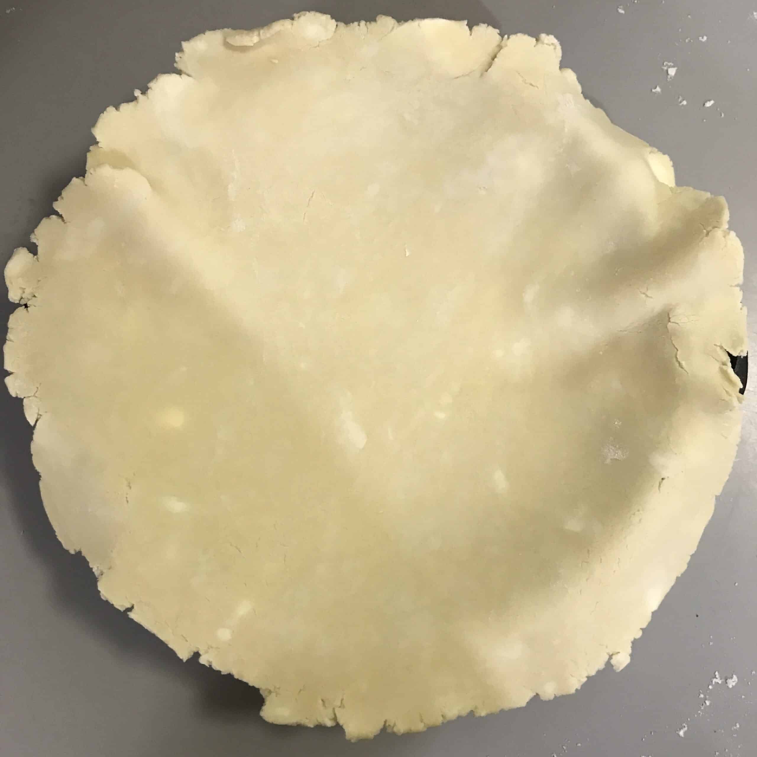 Rolled out pie dough with visible bits of butter