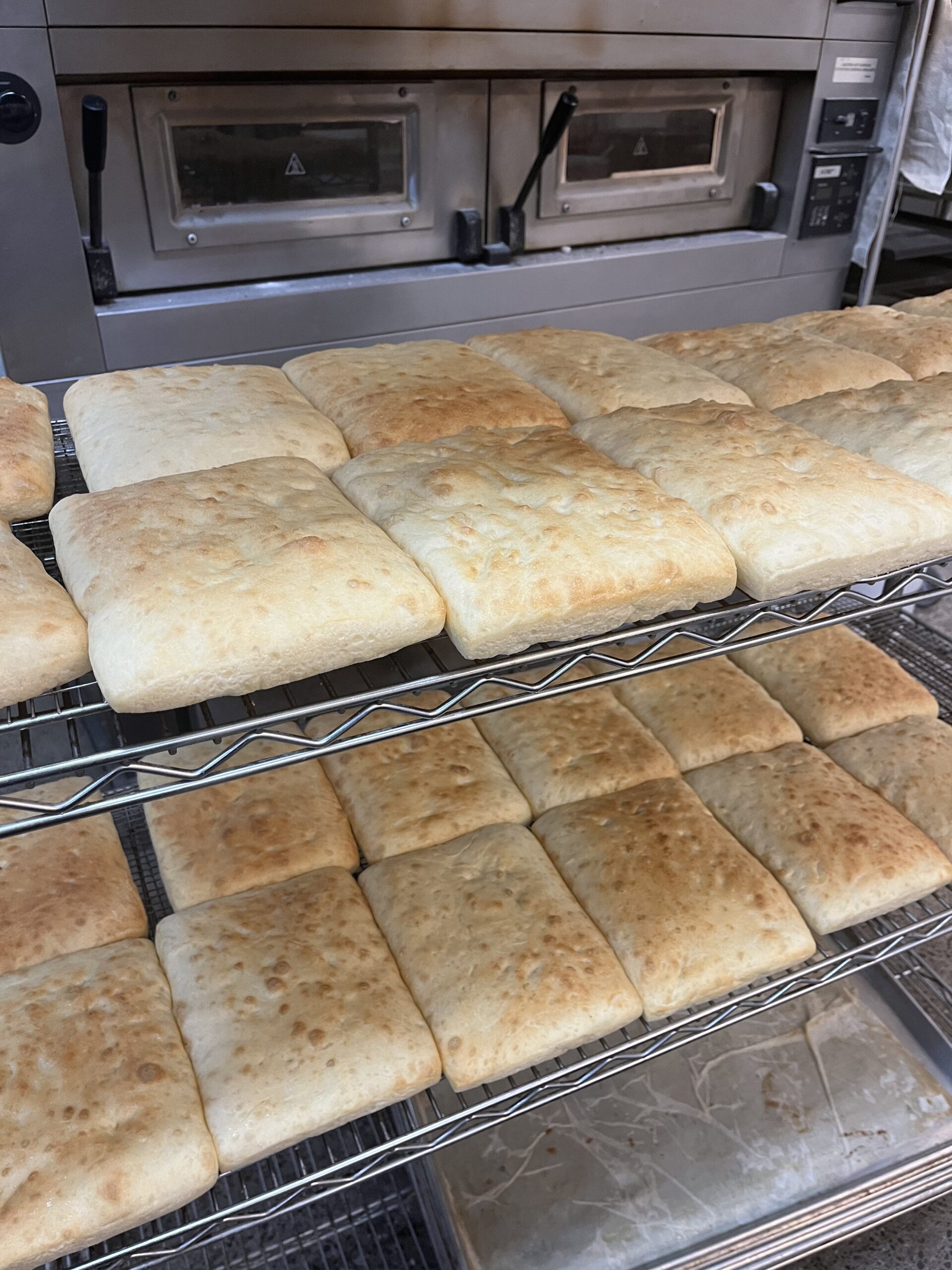 Detroit-style par-baked pizza dough cooling on a rack.