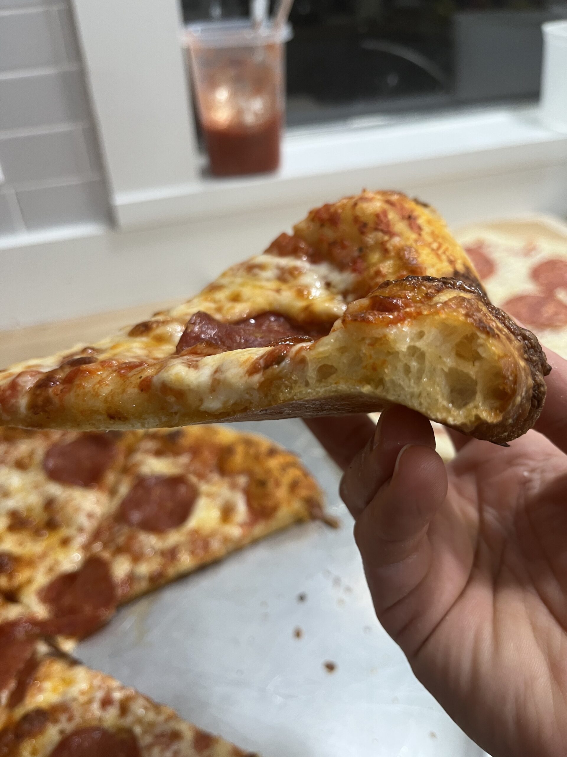 Cross-section of pizza crust of pepperoni pizza.