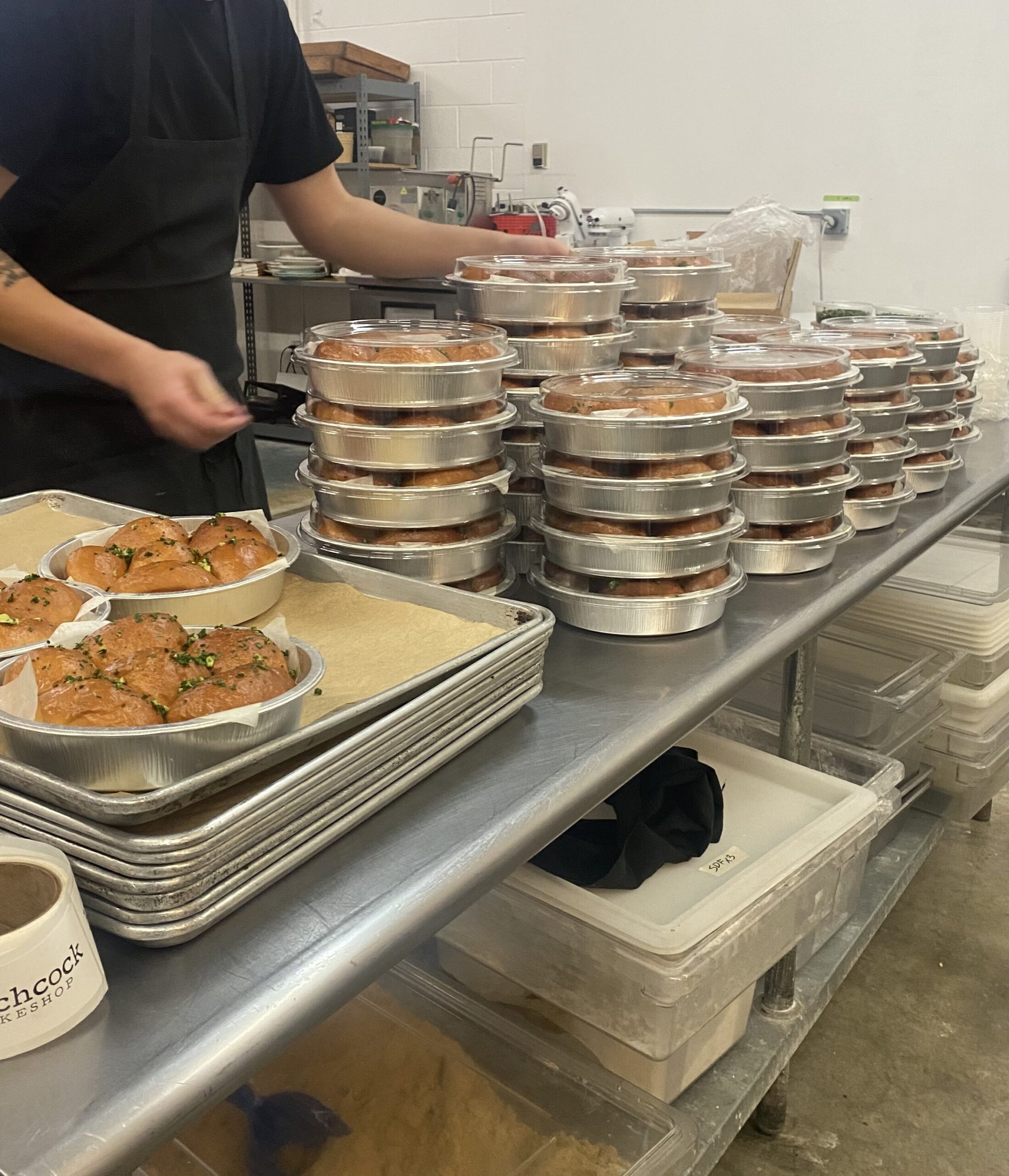 putting lids on dozens of pans of dinner rolls